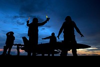 A U.S. Navy aircraft director signals as aviation ordnancemen unload ordnance from an F/A-18E Super Hornet aircraft aboard the aircraft carrier USS Carl Vinson (CVN 70) while under way in the Bay of Bengal Jan. 28, 2011.