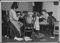 Mrs. Lucy Libertime and family, Johnnie, 4 years old, Mary 6 years, Millie, 9, picking nuts in the basement tenement, December 1911. Photographer: Hine, Lewis. Original public domain image from Flickr