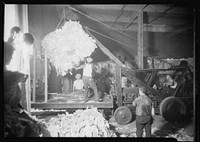 Longshoremen. Large bale being lifted by crane and directed by man on platform, July 1937. Photographer: Hine, Lewis. Original public domain image from Flickr