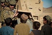 A coalition force member waits for a high-five from children in a village in Farah province, Afghanistan, Dec. 9, 2012.