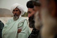 Afghan villagers listen as a coalition forces member speaks with an Afghan district governor during a patrol with Afghan National Army Special Forces to escort the governor to a school in Helmand province, Afghanistan, April 15, 2013.