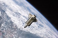 The Space Shuttle Atlantis, backdropped against clouds over Earth