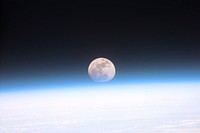 Original caption from NASA: "S103-E-5037 (21 December 1999)--- Astronauts aboard the Space Shuttle Discovery recorded this rarely seen phenomenon of the full Moon partially obscured by the atmosphere of Earth. The image was recorded with an electronic still camera at 15:15:15 GMT, Dec. 21, 1999.".