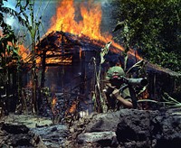 Mỹ Tho, Vietnam. A Viet Cong base camp being burned down. In the foreground is Private First Class Raymond Rumpa, St Paul, Minnesota, C Company, 3rd Battalion, 47th Infantry, 9th Infantry Division, with 45 pound 90 mm recoilless rifle.