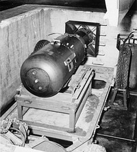 A-Bomb. LB (Little Boy) unit on trailer cradle in pit on Tinian island, before being loaded into Enola Gay's bomb bay. [Note bomb bay door in upper right-hand corner.] , 08/1945. ARC Identifier: 519394.