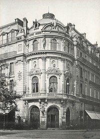 Looking across street towards corner three storey building with highly decorated facade.