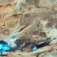 A satellite picture of the Dasht-e Kavir desert in Iran.The patterns you see are formed by different geological layers that have been eroded over thousands of years by wind and sometimes (but not often) rain.The patterns are formed from either horizontal geological layers cut through by topographic changes, or geological formations (folds, domes, etc) in relatively flat terrain.Most of the colours are due to chemical differences in the rocks, whilst the intense blue colours could be due to a range of materials, possibly salt deposits, possibly vegetation, depending on which area of the EM spectrum is represented by blue. I suspect (but don't know, the satellite bands to displayed colours are not mentioned) that the blue colours are salt deposits, but they could equally be other materials too. To be certain, knowledge of the bands to display colours is essential.The black line running horizontally across the image is a sensor drop-out and the data for that line or lines has been irrevocably lost. The linear (but not straight) line running vertically down the middle left is a road.USGS/NASA description: The Dasht-e Kevir, or Great Salt Desert, is the largest desert in Iran. It is primarily uninhabited wasteland, composed of mud and salt marshes covered with crusts of salt that protect the meager moisture from completely evaporating. This image was acquired by Landsat 7’s Enhanced Thematic Mapper plus (ETM+) sensor on October 24, 2000. This is a false-color composite image made using infrared, green, and red wavelengths. The image has also been sharpened using the sensor’s panchromatic band.