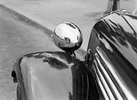 A car at Place de l'Étoile with the Arc de Triomphe reflected in the headlamp.