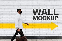 Wall mockup psd with a man walking past in the new normal 