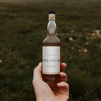 Premium whiskey label mockup psd, man holding bottle outdoors 