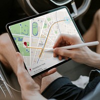 Hand holding stylus pen using map on a tablet in a car