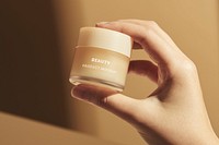 Hand holding beige cream jar