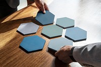 Hands arranging connected hexagon cut out papers