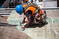 Worker in safety gear uses a hammer on a construction site.