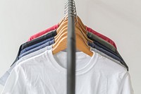 Front view of t-shirts hanging on wooden hangers.