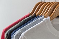 T-shirts hanging on wooden hangers.