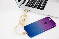 Apple iPhone MacBook with gold charging cable and iPhone.