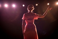 Stage performer waving under lights.