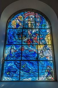 Marc Chagall: Stained glass windows at TudeleyMarc Chagall born Moishe Shagal; 6 July [O.S. 24 June] 1887 – 28 March 1985) was a Belarusian-French artist. An early modernist, he was associated with several major artistic styles and created works in a wide range of artistic formats, including painting, drawings, book illustrations, stained glass, stage sets, ceramics, tapestries and fine art prints. The Chagall windows at Tudeley were commissioned by Sir Henry and Lady d'Avigdor-Goldsmid in memory of Sarah d'Avigdor-Goldsmid, their daughter who died in 1963 at the tragically early age of 21, in a sailing accident off Rye. Sarah d'Avigdor-Goldsmid and her mother had visited the 1961 Louvre exhibition of Chagall's work. The centrepiece of the exhibition were the windows designed for the synagogue of the Hadassah Medical Centre in Jerusalem, depicting the Twelve Tribes of Israel. It was the memory of her daughter's love of these windows that led Sir Henry and Lady d'Avigdor-Goldsmid to commission Chagall to design windows for All Saints Tudeley.