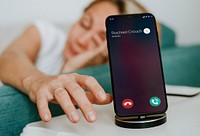 Drowsy woman reaching for her phone to turn off the alarm