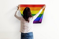Pride flag background, woman decorating wall