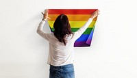 Pride flag background, woman decorating wall