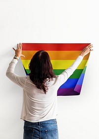 Pride flag background, woman decorating wall