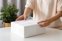 Woman wrapping white gift box. 