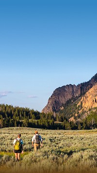 Mountain landscape iPhone wallpaper, travelers walking through grass