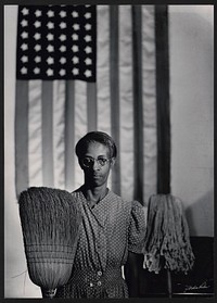 American Gothic. Photograph shows Farm Security Administration employee Ella Watson standing with mop and broom in front of American flag. Sourced from the Library of Congress.