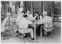 Playing dominoes or cards in front of drug store in center of town in Mississippi Delta, Mississippi. Sourced from the Library of Congress.