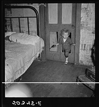 Why open the door, coal miner's child uses the "cat hole." Bertha Hill, West Virginia (Note pipe in one hand, gun in other). Sourced from the Library of Congress.