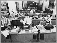 New York, New York. Newsroom of the New York Times newspaper. Reporters and rewrite men writing stories, and waiting to be sent out. Rewrite man in background gets the story on the phone from reporter outside. Sourced from the Library of Congress.