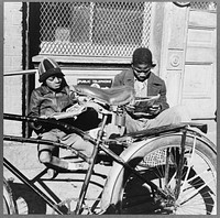 Washington, D.C. Two  boys reading the funnies on a doorstep. Sourced from the Library of Congress.