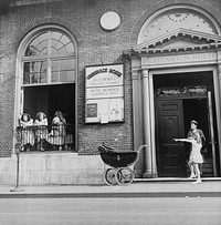 New York, New York. A mother and child at the Greenwich House entrance where the little girl receives day care while her mother works. Sourced from the Library of Congress.