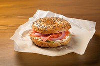 Close-up of Lox Bagel with onions on paper sheet.  