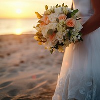 Closeup groom and bride have bouquet at the sunset beach, focus on bouquet.  