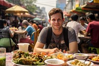 American man eating padthai food restaurant street. 