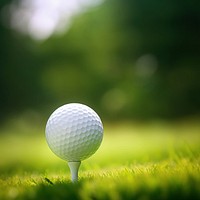 photo of a close up the golf ball on tee pegs ready to play, light green, natural light. 