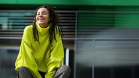 a woman with dreadlocks smiling wearing lime green sweater, playful poses, close up, outdoor city, cool. AI generated Image by rawpixel. 