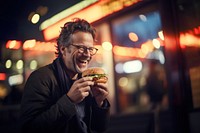 An middle aged man eating burger biting adult food. 