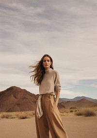 A woman standing wearing a minimal colorful outfit outdoors desert nature. 