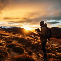 front-left view Photo of a man holding camera, taking picture in the wild in a chilly day. 