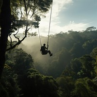 Photo of a man playing zipline through jungle. 