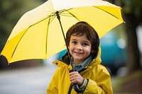 Smiling kid wearing a yellow raincoat umbrella holding child. 