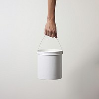 Hand carrying a paint bucket container lighting standing. 