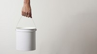 Hand carrying a paint bucket container lighting standing. 