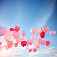 a real photo of heart-shaped balloons floating up in the air. 