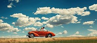 Photo of couple driving in red vintage car on countryside. 