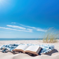 Book on the picnic blanket in beach white sand.  